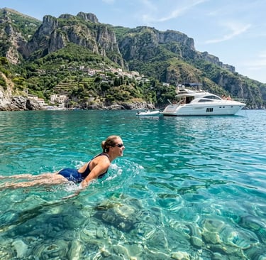 Woman swimming in crystal clear turquoise water near anchored yacht at Nerano Bay