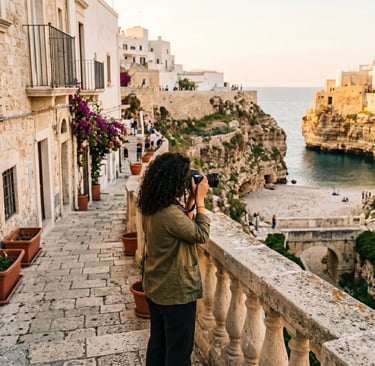 Woman with DSLR camera photographing Polignano a Mare cliffs and Lama Monachile beach from balcony