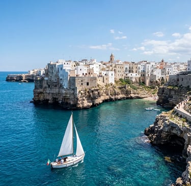 White sailboat sailing in front of Polignano a Mare cliffs and white houses on Adriatic coast