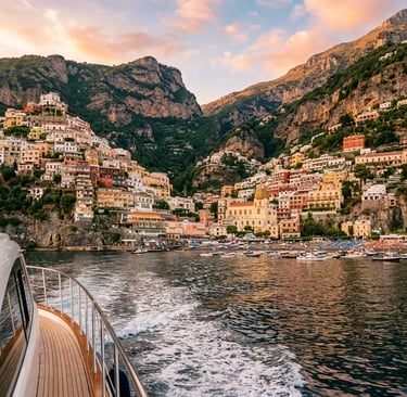 Positano's pastel hillside buildings viewed from a boat deck at golden hour