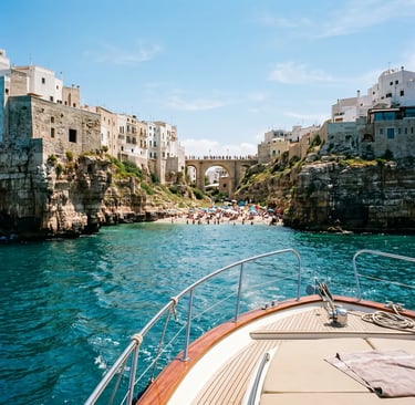 Yacht bow approaching Lama Monachile beach and Roman bridge in Polignano a Mare from the sea