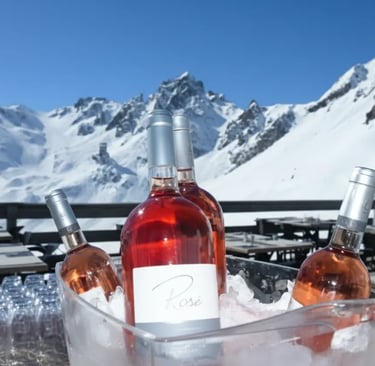 Bottles of rosé wine chilled in an ice bucket with a panoramic view of snow-capped Alpine peaks in t
