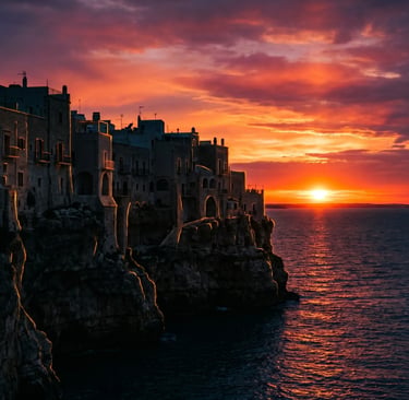 Silhouette of Polignano a Mare cliff houses against orange and purple sunset sky over Adriatic Sea