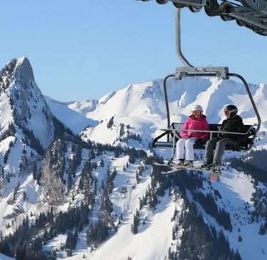 Skiers riding a chairlift over rocky mountain peaks in a Swiss ski resort.