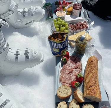 Aesthetic winter scene of a wooden tray with pastries and a mug of coffee on the snow, with a scenic
