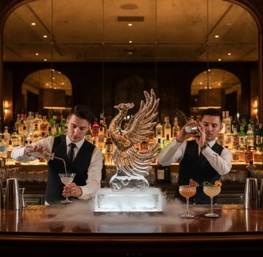 Two professional bartenders crafting cocktails behind a bar featuring a dramatic phoenix ice sculptu