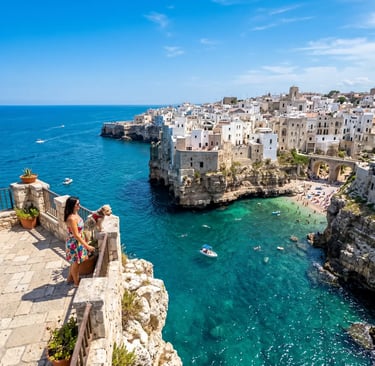 Woman with small dog admiring Polignano a Mare turquoise cove and whitewashed cliffside houses