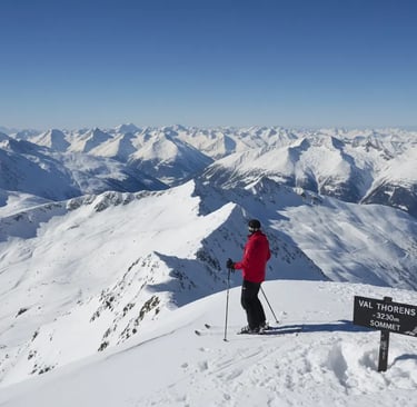 Lone skier enjoying the view from a snowy mountain summit during a sunny winter day.