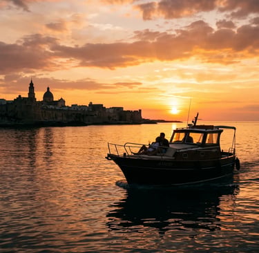 Couple enjoying private sunset boat tour near Monopoli old town silhouette, Puglia, Italy.