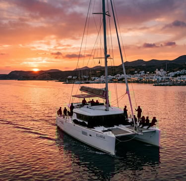 Catamaran sailing back to Adamas port in Milos under orange sunset sky