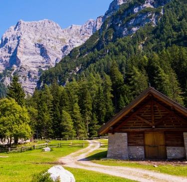Rustic wooden barn on green alpine meadow below dramatic Dolomite cliffs