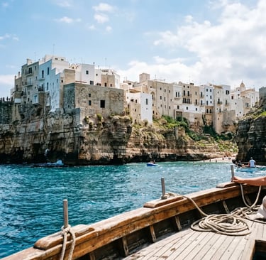 View of Polignano a Mare white cliffs from a wooden sailing boat deck