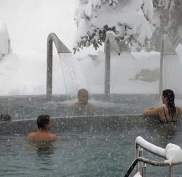 Close-up of people relaxing under a warm waterfall massage in an outdoor hot spring while it is snow