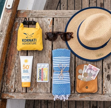 Flat lay of straw hat, sunscreen, towel and sunglasses for a Croatia island hopping tour.
