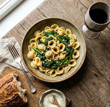 Handmade orecchiette pasta with cime di rapa, bread and red wine on rustic wooden table