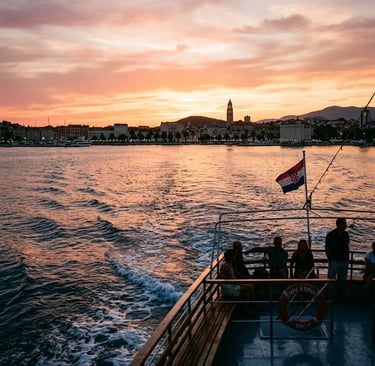 Boat returning to Split at sunset with Croatian flag and city skyline in golden light