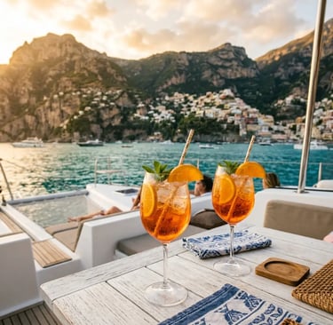 Two aperol spritz cocktails on luxury catamaran deck with Amalfi Coast sunset view