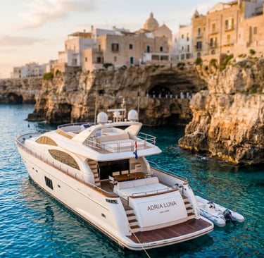 Luxury private charter yacht anchored in turquoise Adriatic water beneath Polignano a Mare cliffs