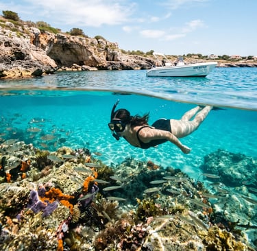 Woman snorkeling over colorful reef with fish near small tour boat in Salento cove, Puglia