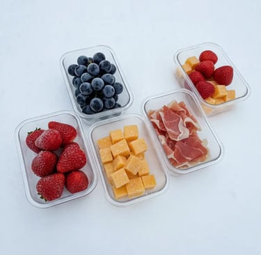 Prepped snack containers with strawberries, blueberries, cheese cubes, and prosciutto organized on t