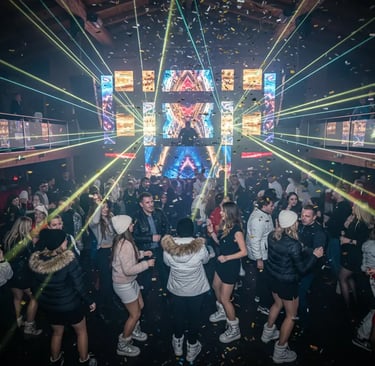 High-energy crowd dancing in an upscale Ischgl nightclub with vibrant laser lights and falling confe
