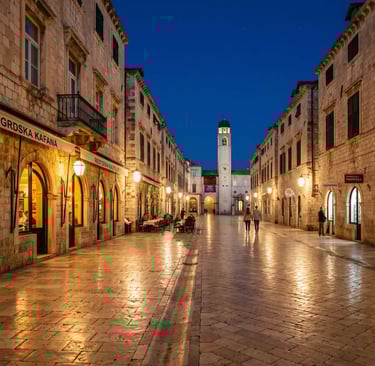 Empty Stradun marble boulevard in Dubrovnik lit by warm street lamps at dusk