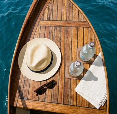 Wooden Caprese gozzo deck with straw hat, chilled drinks and linen towel over turquoise sea