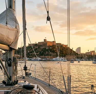 Montjuïc castle seen through yacht rigging at sunset returning to Barcelona harbour