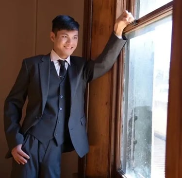 a man in a suit and tie standing in front of a window