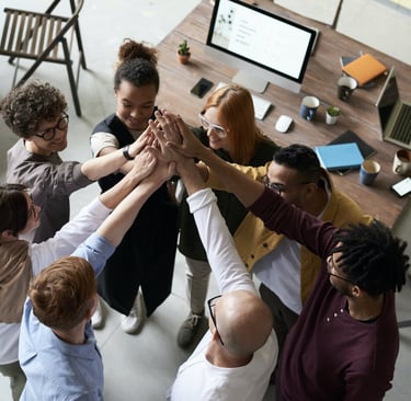 A group of people in an office, hands raised, ready to assist.