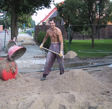 Jörg Grube steht auf der Baustelle und schaufelt Sand in den Botonmischerr