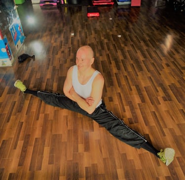 Jörg Grube im Fitnessraum auf dem Boden im Spagatsitz