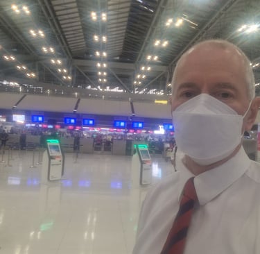 Jörg Grube mit Maske, weißem Hemd und Krawatte im leeren Flughafengebäude