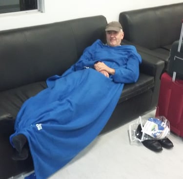 Jörg Grube mit Schirmmütze und Decke auf liegend auf einer Couch