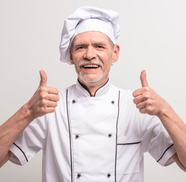 a chef in a white chef's uniform with thumbs up
