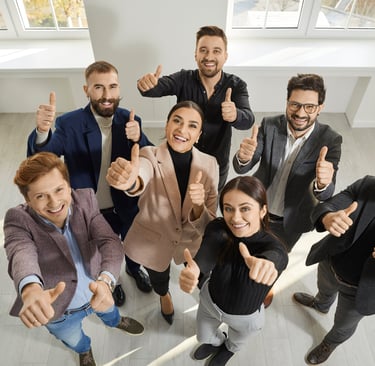Grupa osób patrząca w górę z kciukami do góry