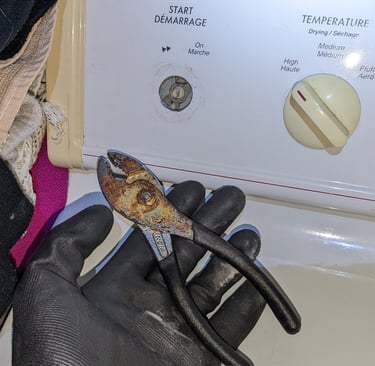 A plier in top of an electric dryer