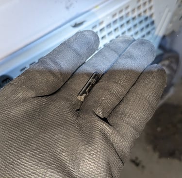 A person holding a pin in front of a clothes dryer