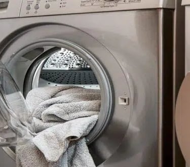a dryer and front load washer and some towels inside the dryer
