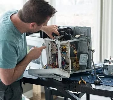 a person repairing a microwave on a table