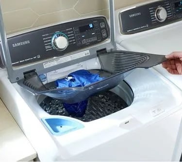 samsung washer and dryer shown by a person holds the top basket