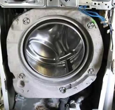 Front panel of a washer is removed for pump repair