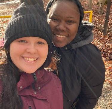 two women standing next to each other. one is in a burgundy jacket and the other is in a black one. 