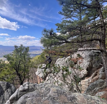 a person's feet in the air with a person standing on a rock