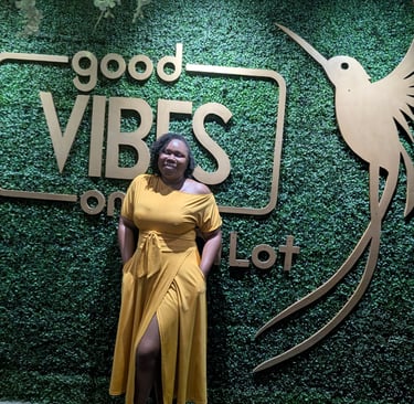 a woman in a yellow dress standing in front of a sign that says good vibe