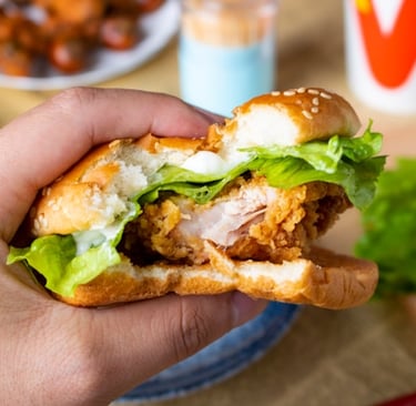Chick-fil-A® catering menu, a person holding a burger with chicken and lettuce