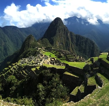 Scenic view of Machu Picchu ruins surrounded by lush green mountains in Peru.