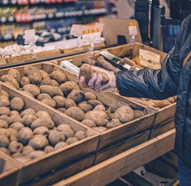 person selecting potatoes at grocery store