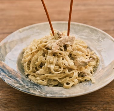 Creamy chicken fettuccine alfredo pasta served in a ceramic bowl on a rustic wooden table.