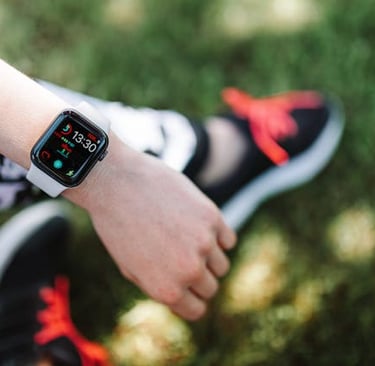 A person wearing a modern smartwatch with a fitness tracker on their wrist while sitting outdoors.